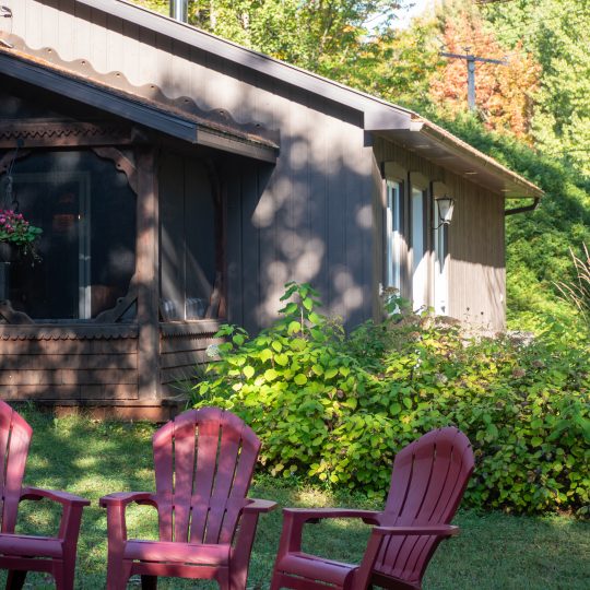Le chalet Le Pêcheur en été, avec ses chaises Adirondack et ses fleurs