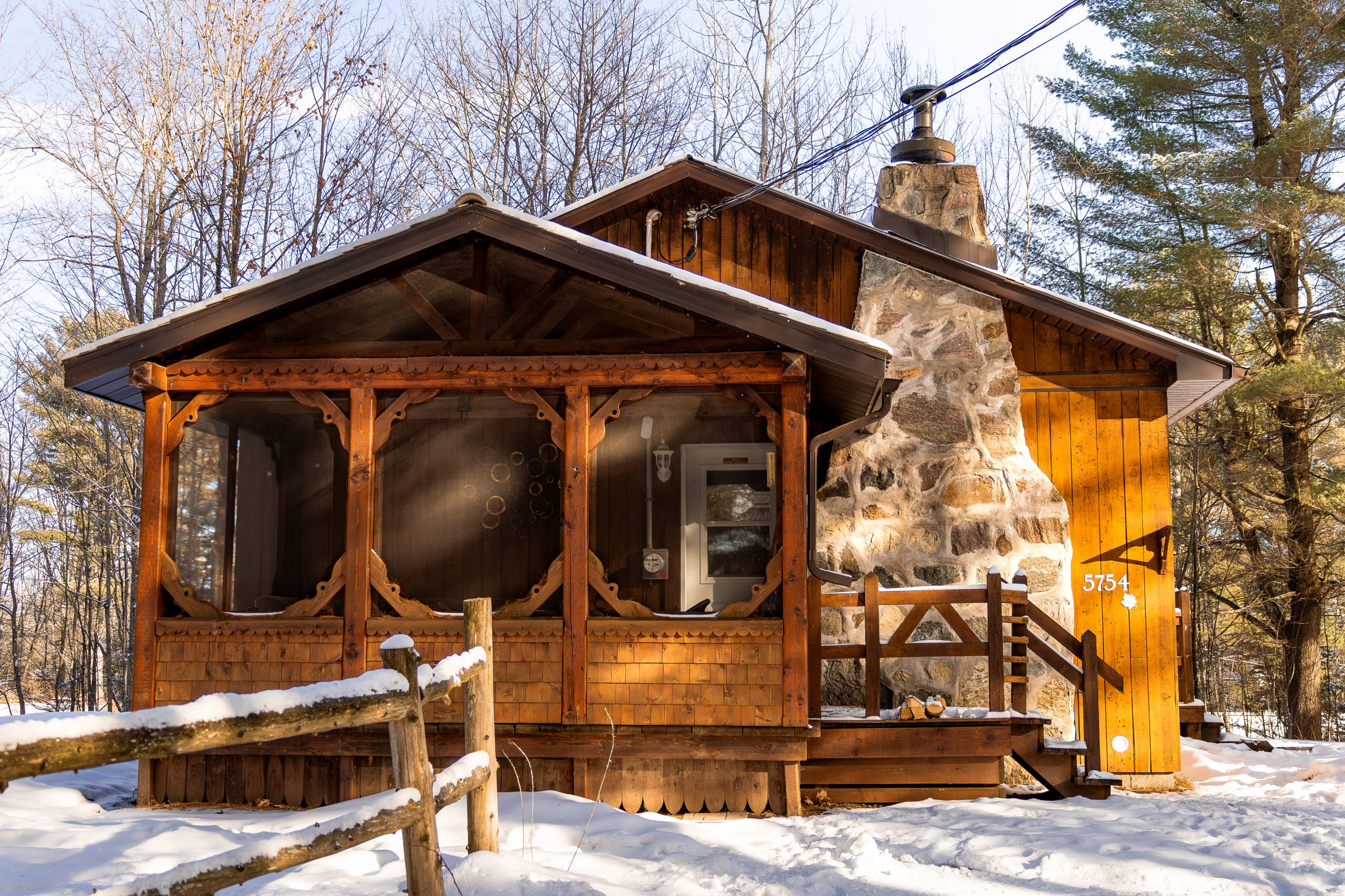 Le chalet La Légende des pins en hiver, avec sa véranda et sa cheminée de pierre